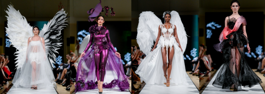 Four models walk a runway wearing elaborate fantasy costumes: a white angel outfit with large wings, a shiny purple floral ensemble with a wide-brimmed hat, a white feathered angel look, and a dramatic black-and-pink gown.