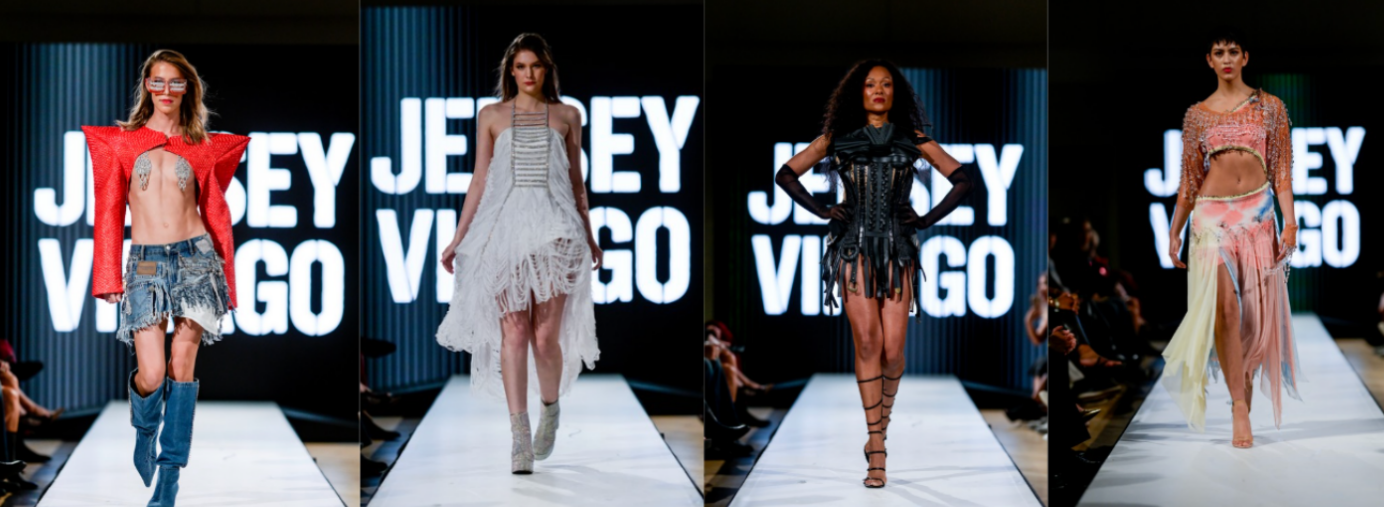 Four models walk a runway wearing creative, fringe-filled outfits in denim, white, black, and pink tones. The background displays large, bold letters spelling "JENNY VARGO".