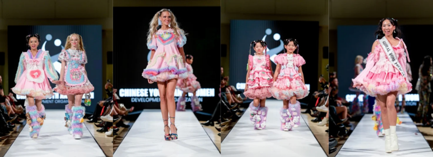 Four models, including children and adults, walk a runway in pastel pink, ruffled dresses with colorful, whimsical details and plush accessories at a fashion show. The background displays a screen with white text.