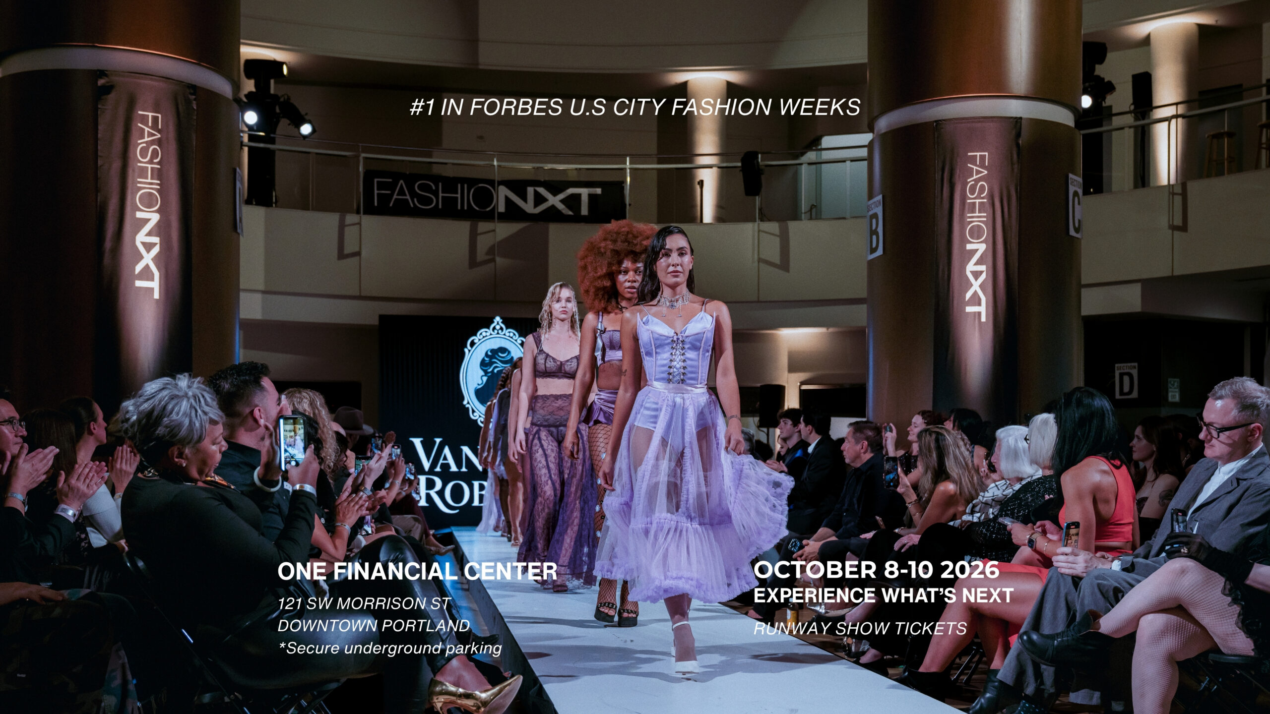Models in purple dresses walk a runway at a fashion show. The audience watches, and banners display &ldquo;FashionNXT.&rdquo; Event details for Portland, October 8-10, 2026, appear at the bottom.